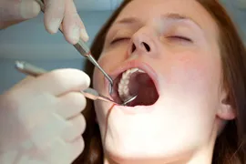 Woman having her teeth checked with dental tools.